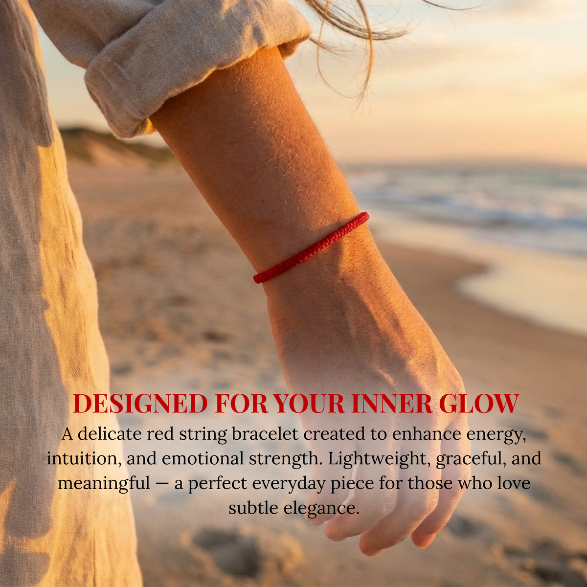 Photograph of an arm adorned with a delicate red string bracelet, bathed in warm golden sunset light against a soft focus sandy beach and gentle ocean waves