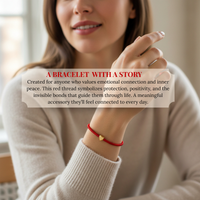 Photography of a woman wearing a symbolic red thread bracelet with a gold heart charm on her wrist, a meaningful accessory against her soft beige sweater