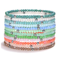 A stack of colorful beaded bracelets featuring faceted glass beads in a gradient of pastel blues, greens, peaches, pinks, and browns, interspersed with shiny silver-tone metallic spacer beads on a clean white studio background