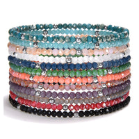 A stack of colorful faceted beaded bracelets featuring silver accent beads on a crisp white background