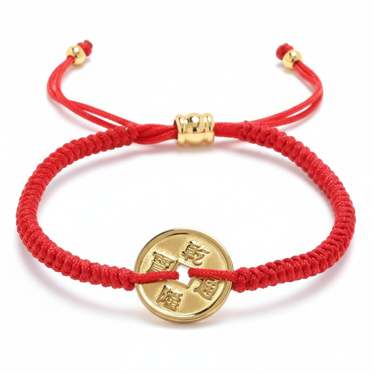 A red braided string bracelet featuring a gold-colored Chinese coin charm with a square hole and Qianlong Tongbao characters, secured with an adjustable sliding knot and gold beads