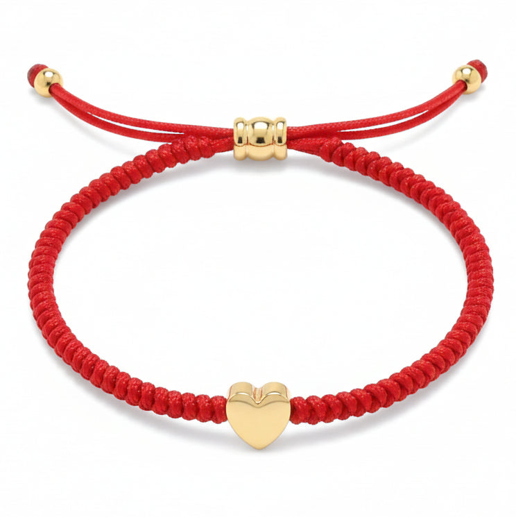 Red braided string bracelet featuring a central gold heart charm and an adjustable gold bead knot closure